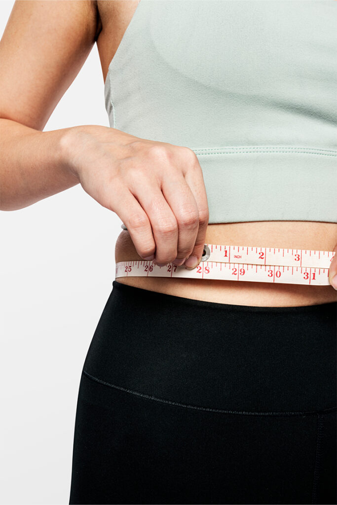 Person measuring physical progress, highlighting simple and effective strategies to cultivate a nourished body and healthy weight loss.