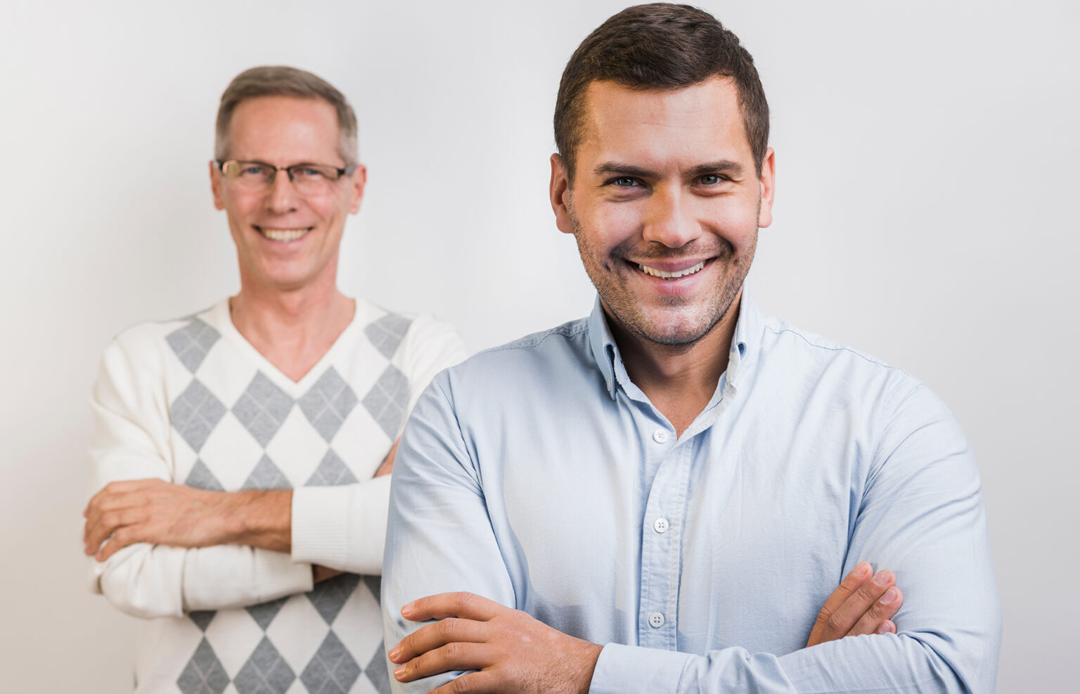Photo of father and son (50 and 30 years old) posing confidently in light shirts, inspiring longevity, energy, and a healthy lifestyle focused on testosterone and male performance.